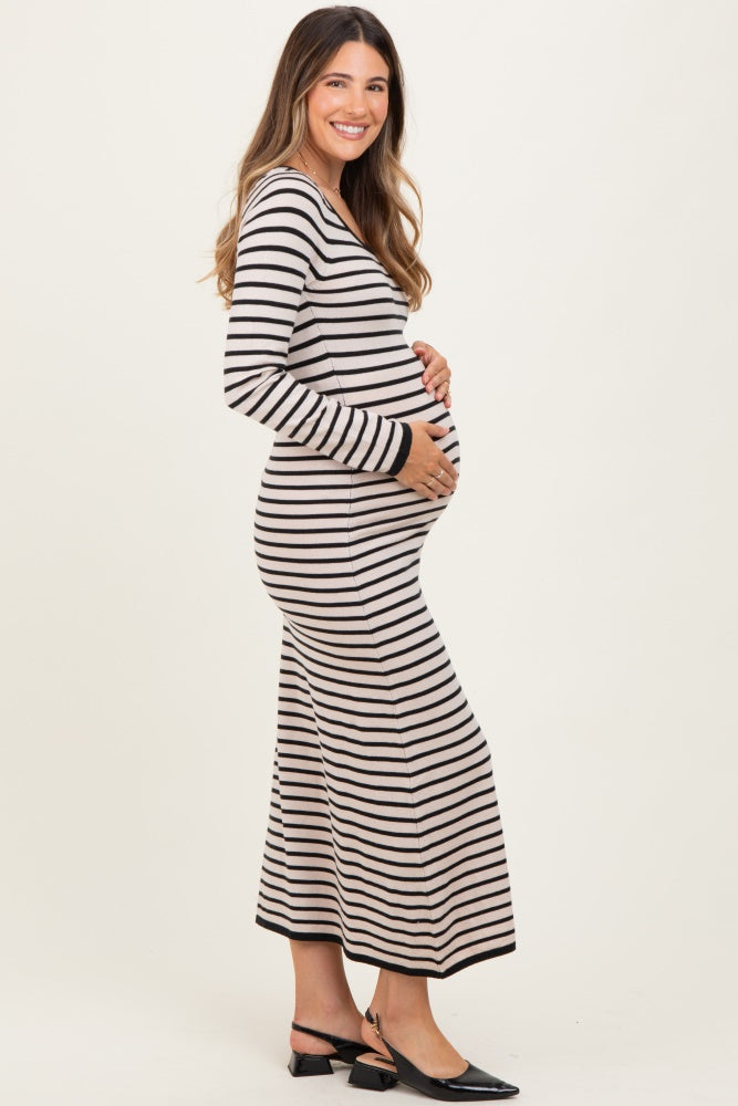 woman wearing a striped long sleeve maternity dress and gently cradling her baby bump
