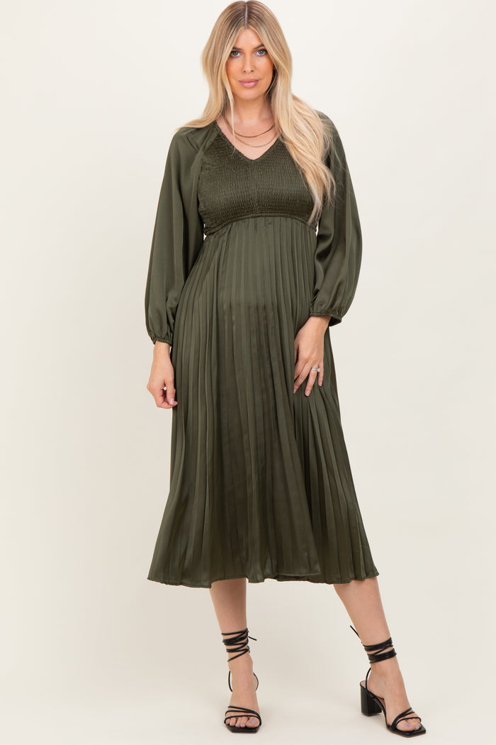 woman wearing an olive green pleated midi dress with puff sleeves and a fitted bodice