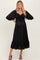 woman wearing a black maternity dress with puff sleeves, ruched bodice, and ruffled hem