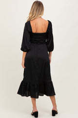 woman wearing a black maternity dress with a smocked bodice and ruffled hem, shown from the back