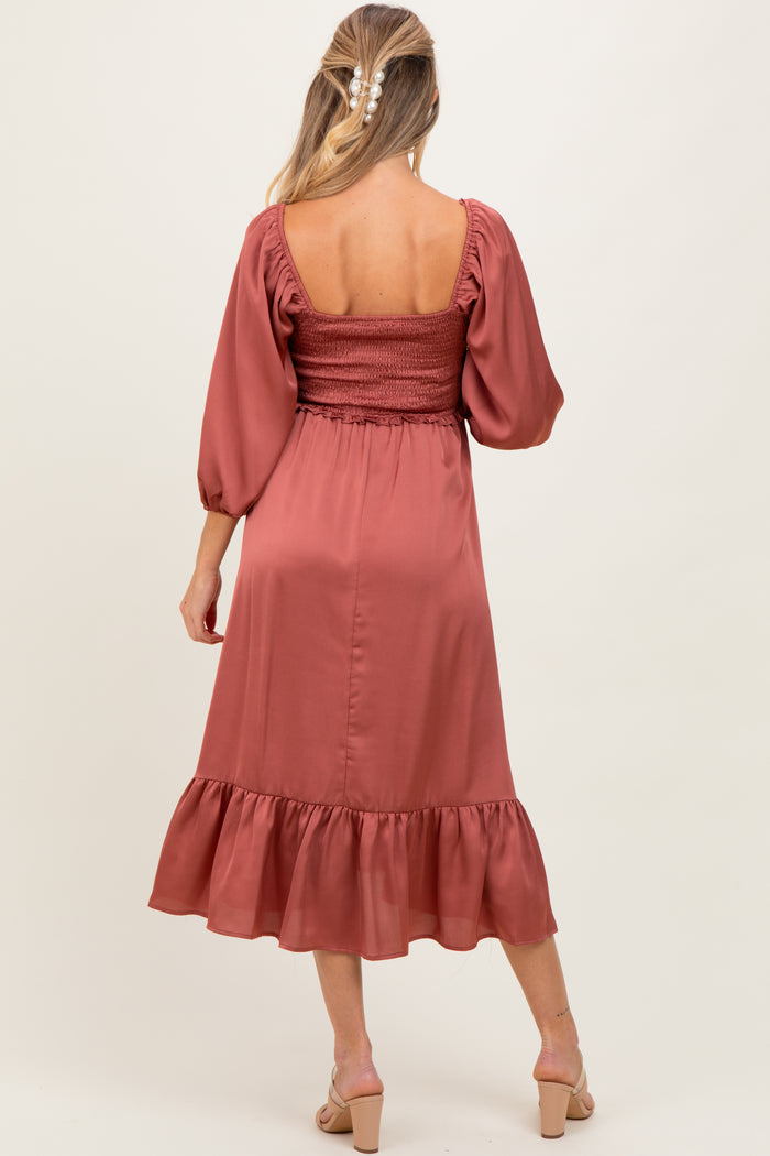 woman wearing a rust-colored maternity dress with smocked bodice and ruffled hem, showing her back