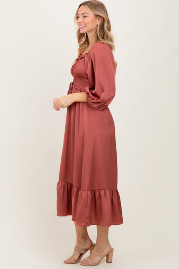 woman wearing a rust-colored midi dress with smocked bodice and puff sleeves, styled with nude heels