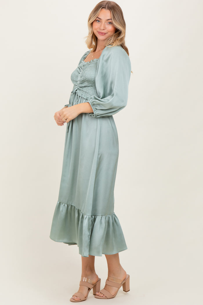 woman wearing a sage green smocked midi dress with ruffled hem and long sleeves