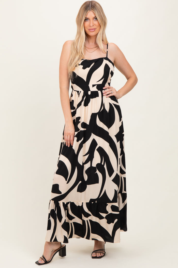 woman wearing a black and beige abstract print maxi dress with spaghetti straps and a tiered hem