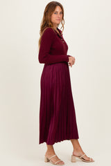 woman wearing a burgundy long sleeve pleated dress with a button-up neckline and heeled sandals
