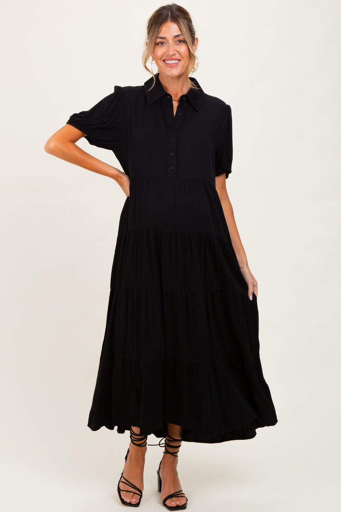 woman wearing a black tiered button-up maternity dress with short puff sleeves and a visible baby bump