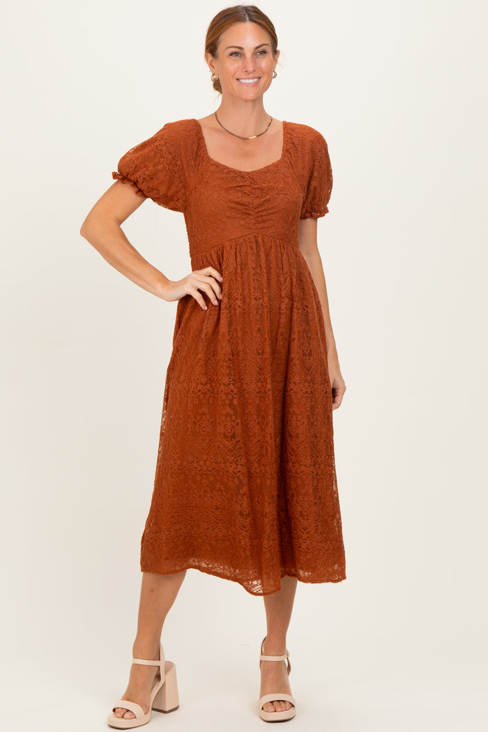 woman wearing a rust-colored lace midi dress with puff sleeves and a square neckline in a standing pose
