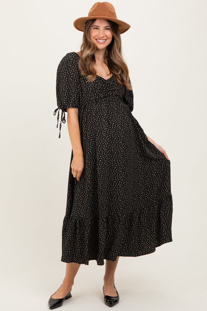 woman wearing a black maternity dress with white polka dots and puff sleeves, smiling and holding her baby bump