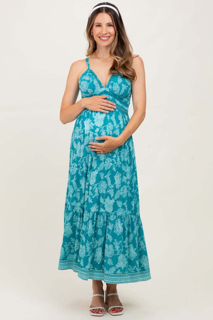 woman wearing a turquoise floral maternity maxi dress and holding her baby bump
