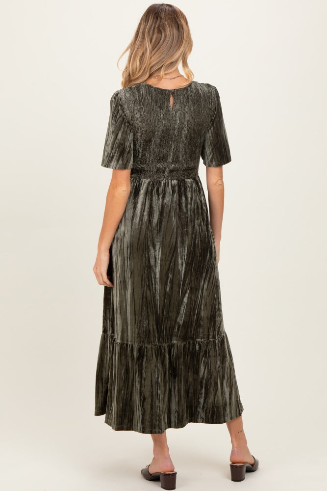 woman wearing a dark green maternity dress with a tiered hem and short sleeves, showing the back view