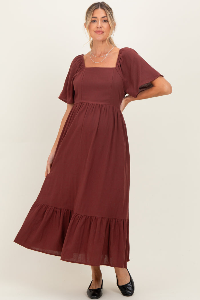 woman wearing a burgundy maternity dress with puff sleeves and a tiered skirt