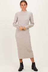 woman wearing a beige ribbed midi dress with long sleeves and button detailing on the cuffs