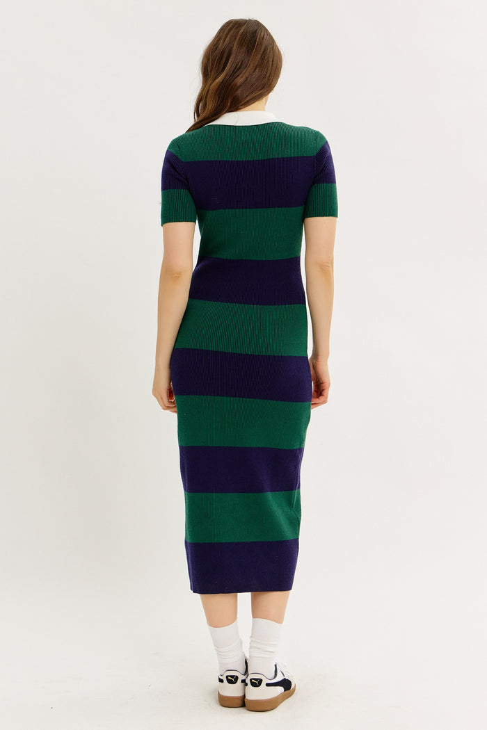 woman wearing a green and navy striped short sleeve midi dress, seen from the back, paired with white socks and sandals