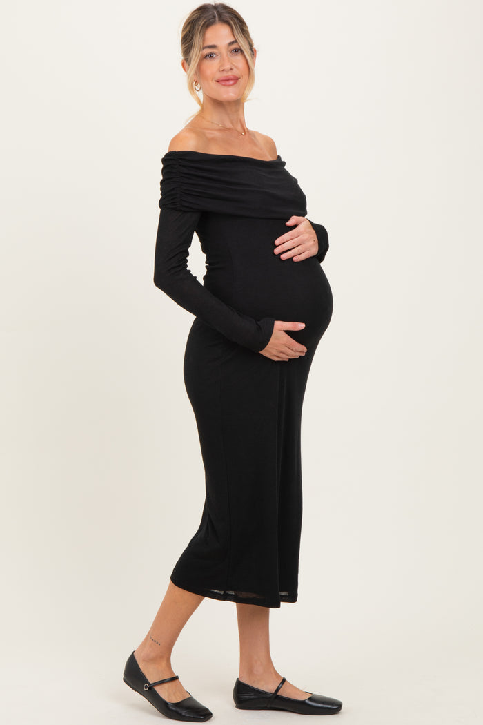 woman wearing a black off-shoulder maternity dress showcasing her baby bump