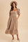 woman wearing a taupe puff sleeve midi dress with a square neckline and ruffled hem, styled with a hat and flats