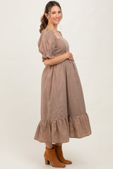 woman wearing a brown checkered maternity dress with puff sleeves and a ruffled hem, showing her baby bump