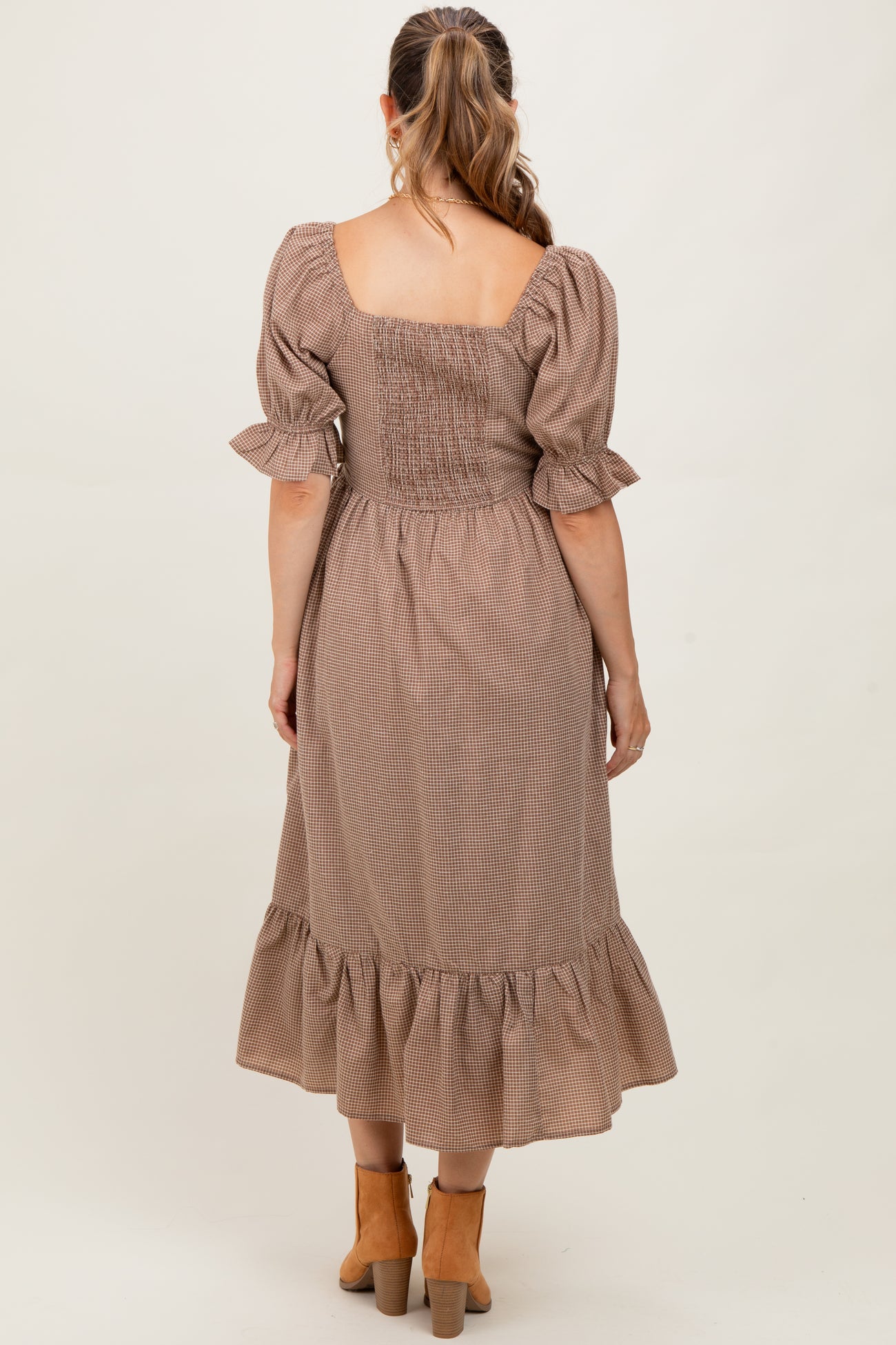 woman wearing a brown checkered maternity dress with a smocked bodice and ruffled hem, showing her back