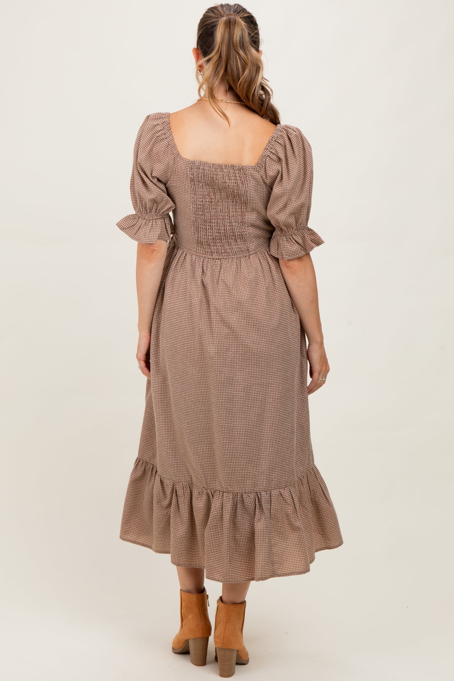 woman wearing a brown checkered maternity dress with a smocked bodice and ruffled hem, showing her back