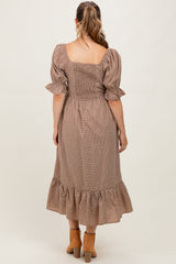woman wearing a brown checkered maternity dress with a smocked bodice and ruffled hem, showing her back