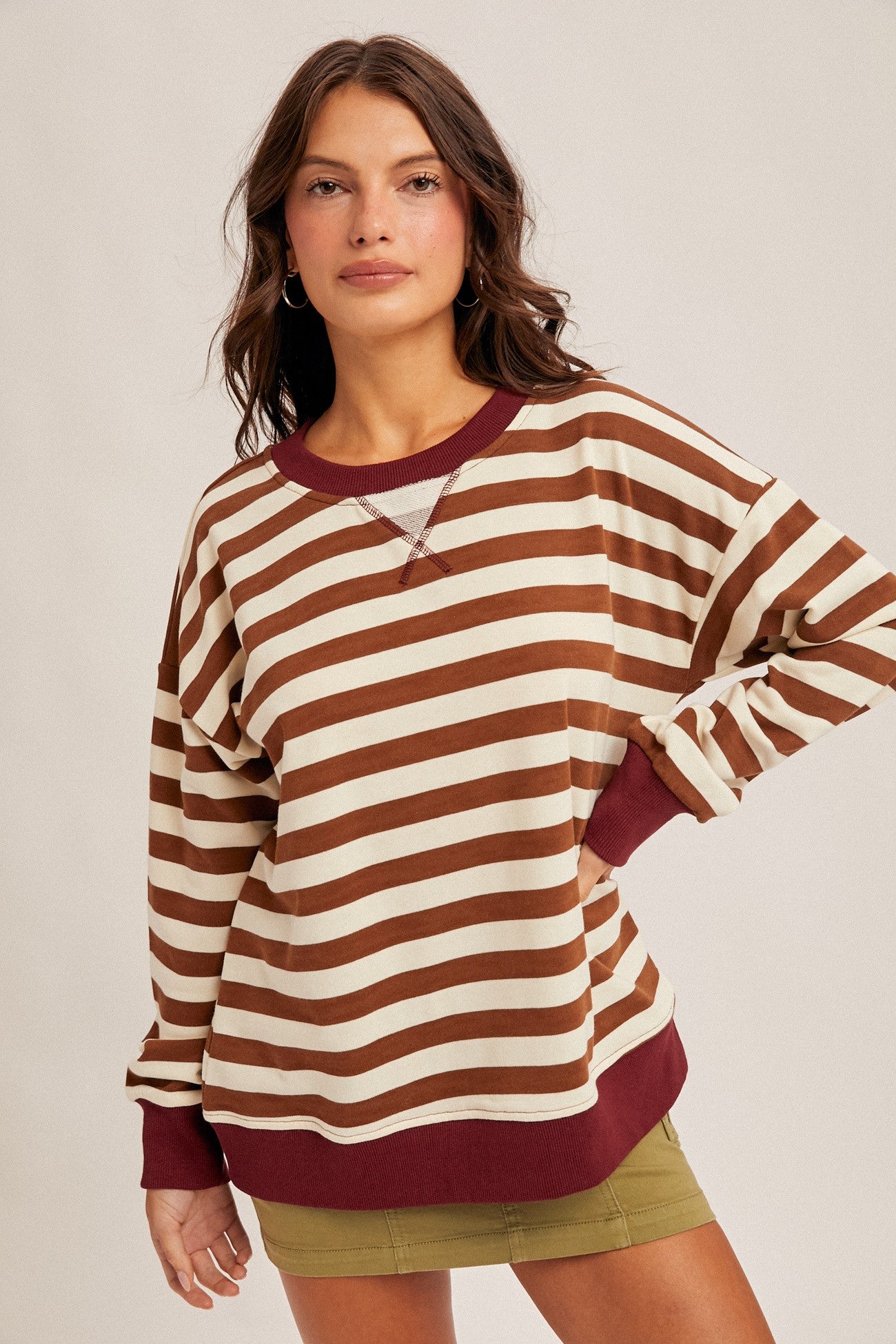 woman wearing a brown and cream striped oversized sweatshirt with maroon accents and a relaxed fit
