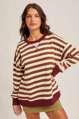 woman wearing a brown and cream striped oversized sweatshirt with maroon accents and a relaxed fit