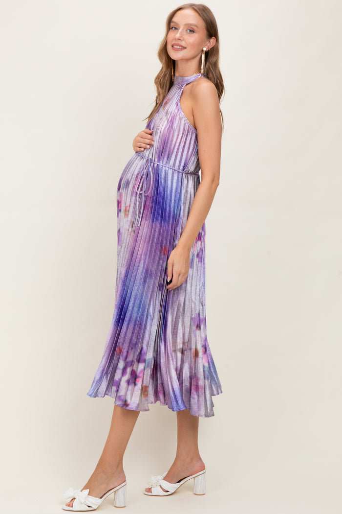 woman wearing a purple tie-dye halter neck maternity dress with a baby bump, styled with white sandals