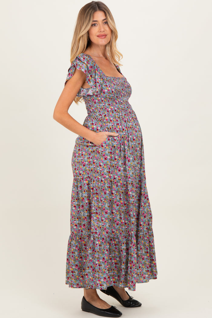 woman wearing a floral print maternity maxi dress with ruffled sleeves, pockets, and a visible baby bump