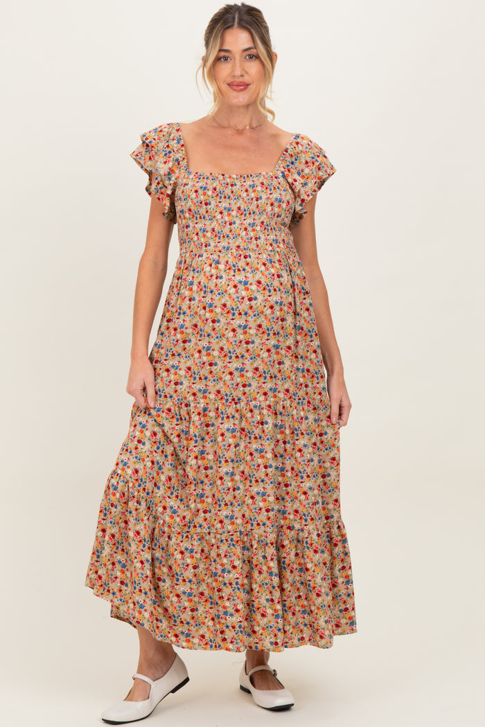 woman wearing a floral print maternity maxi dress with ruffle sleeves and a smocked bodice, showcasing her baby bump