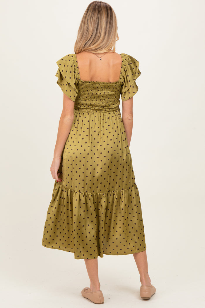 woman wearing a green polka dot maternity dress with ruffled sleeves and a smocked bodice, showing her back