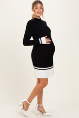 woman wearing a black and white ribbed maternity dress with a fitted bodice and flared hem, showing her baby bump