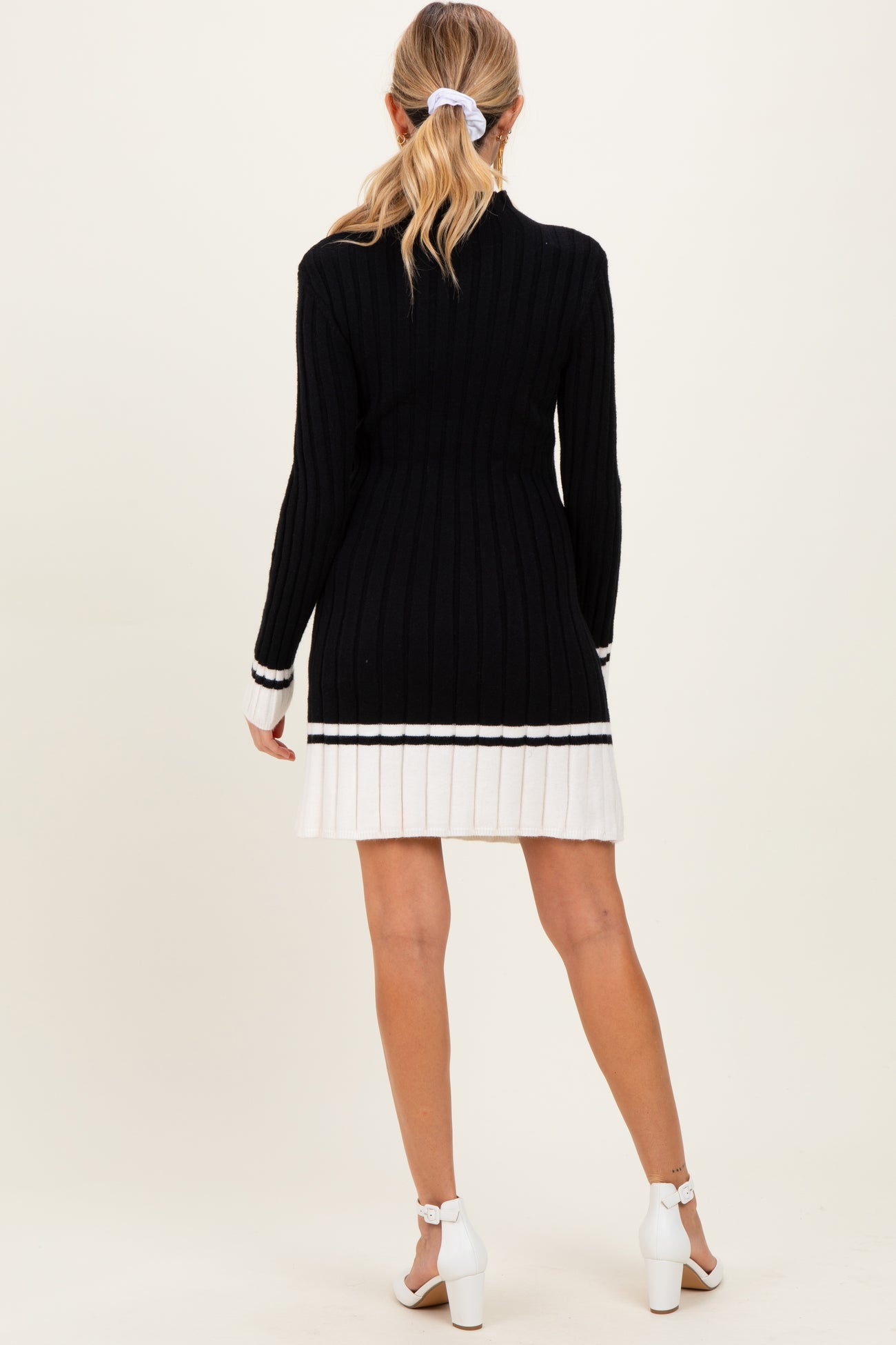 woman wearing a black and white striped maternity sweater dress with ribbed texture, displaying a baby bump