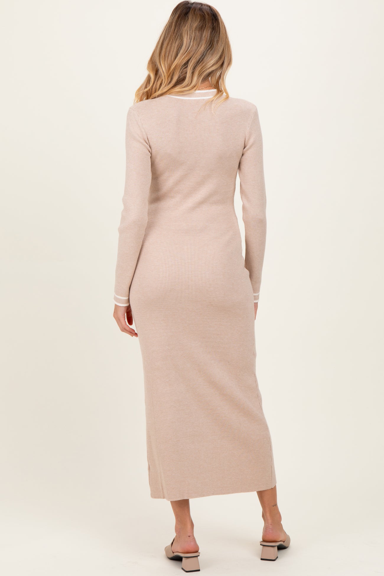 woman wearing a light beige ribbed maternity maxi dress with long sleeves and a side slit