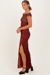 woman wearing a burgundy off-the-shoulder maxi dress with a thigh-high slit and floral pattern, styled with black heels