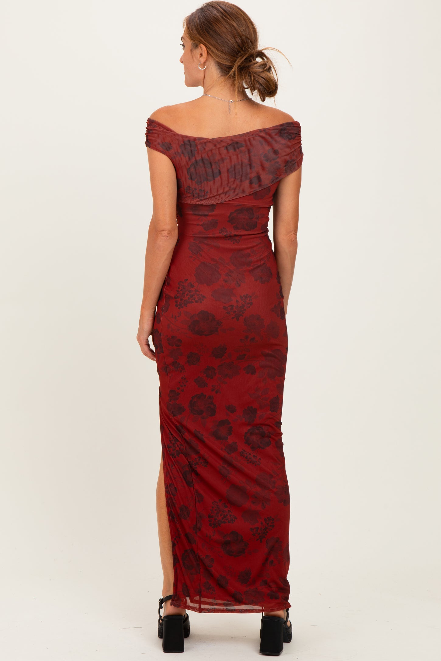 woman wearing a burgundy off-the-shoulder maxi dress with floral print and side slit, view from the back