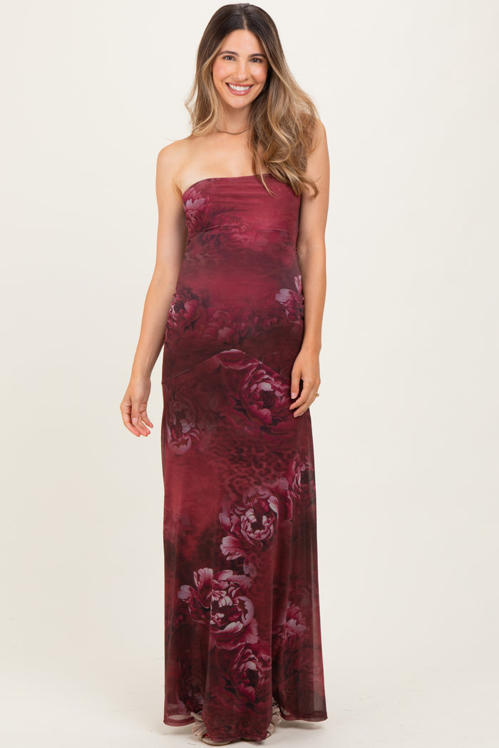 woman wearing a burgundy strapless maternity maxi dress with a floral pattern and a visible baby bump