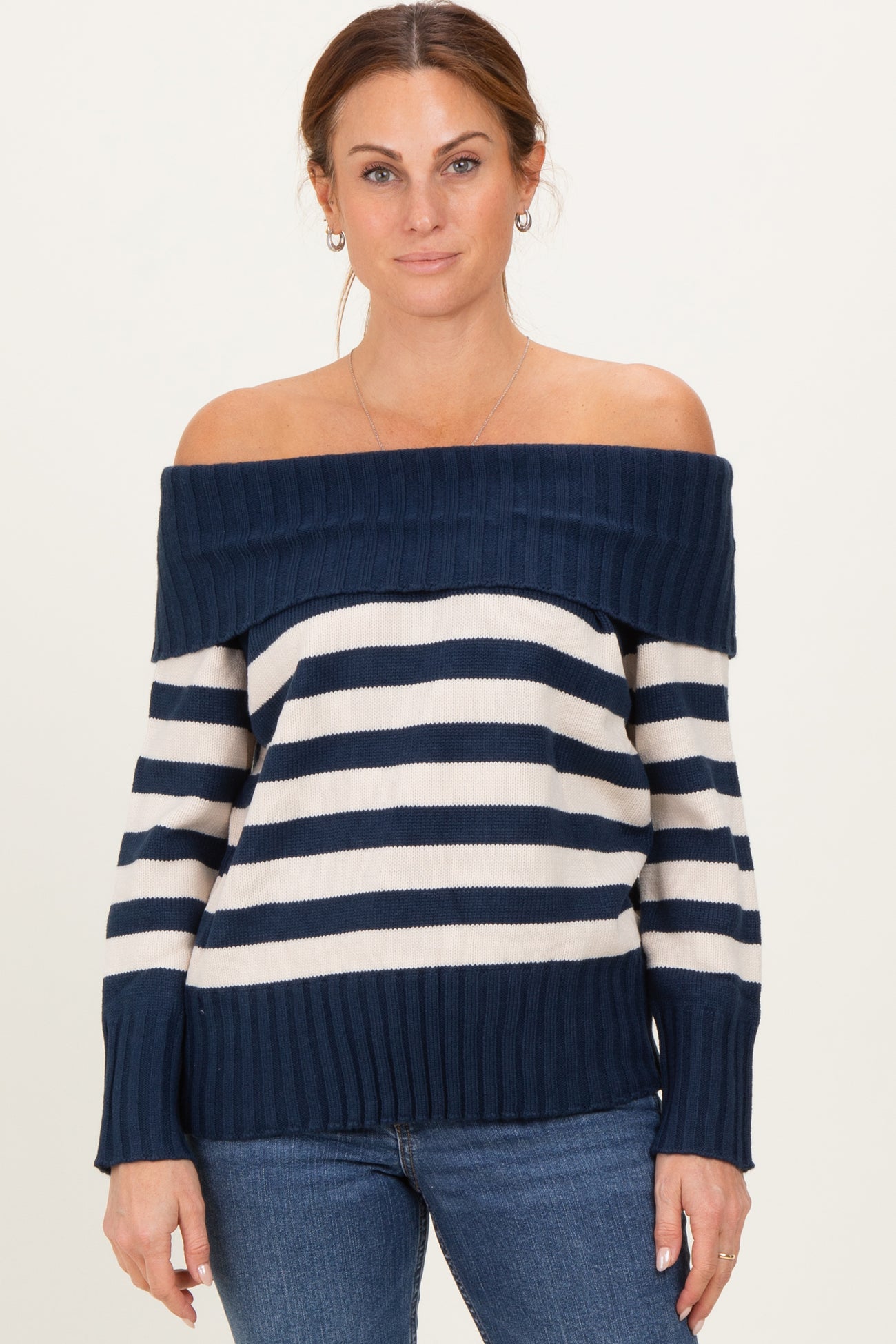 woman wearing a navy and white striped off-the-shoulder sweater paired with blue jeans