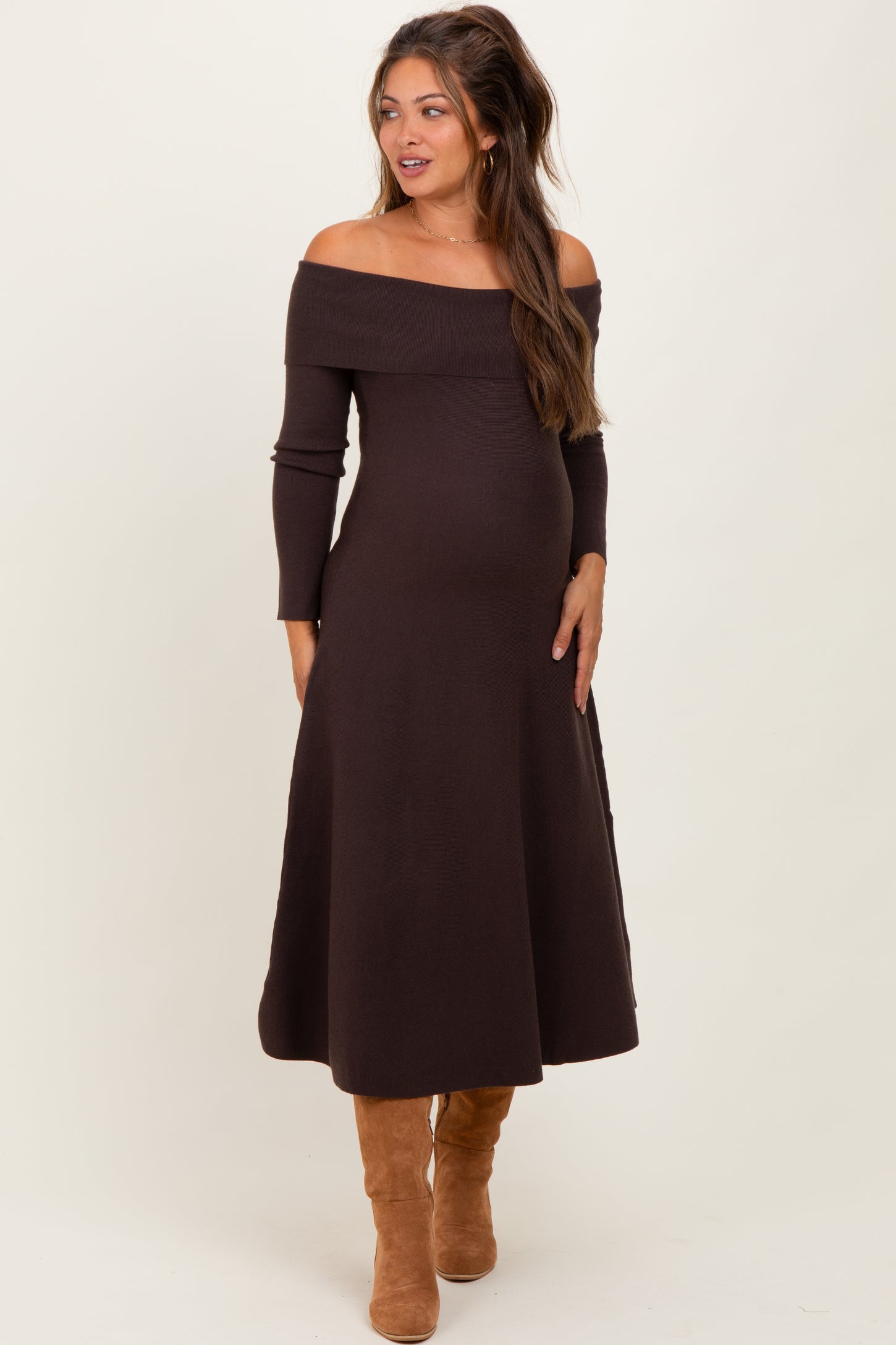woman wearing a chocolate brown off-shoulder maternity dress with long sleeves and a visible baby bump