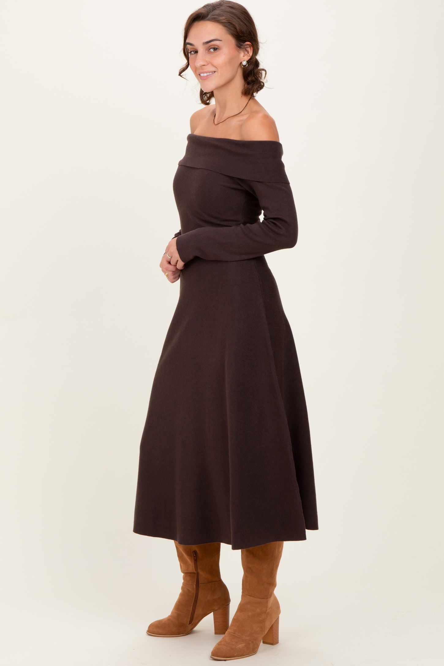 woman wearing a dark brown off-the-shoulder long sleeve dress and tan suede knee-high boots