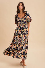 woman wearing a navy blue floral maxi dress with puff sleeves and a tiered skirt