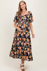 woman wearing a black maternity maxi dress with floral print and short puff sleeves, holding her baby bump