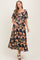 woman wearing a black maternity maxi dress with floral print and short puff sleeves, holding her baby bump