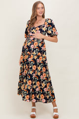 woman wearing a navy floral maternity maxi dress and holding her baby bump