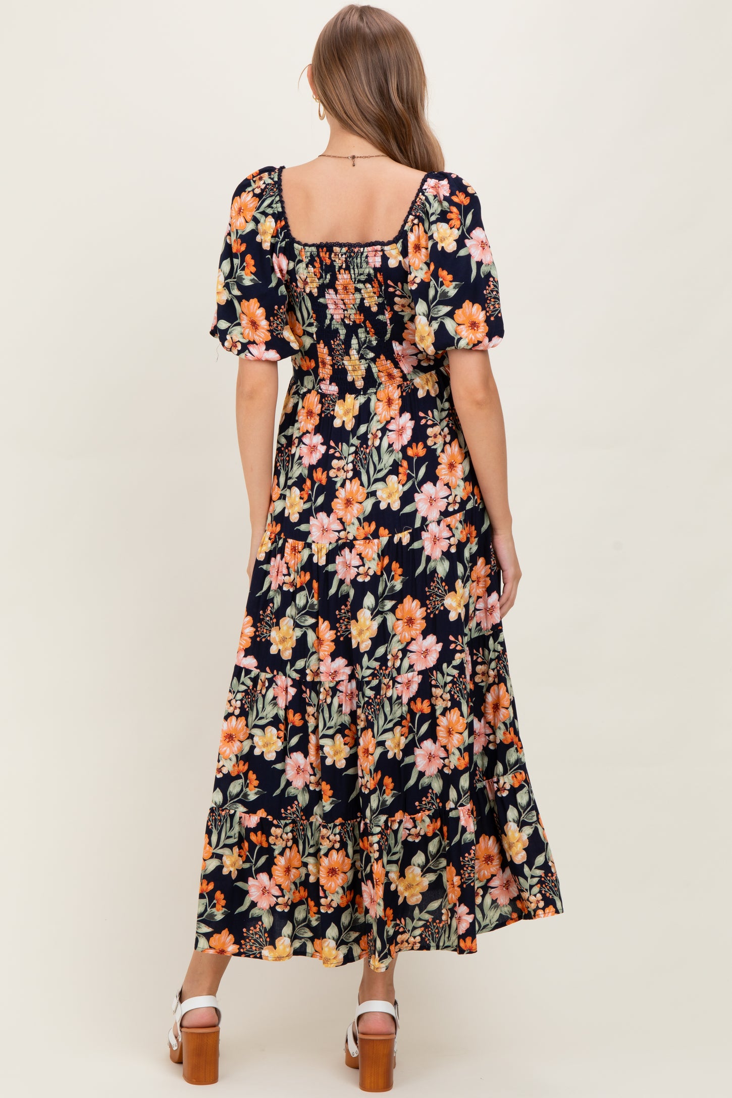 woman wearing a floral print maternity maxi dress with short puff sleeves and a square neckline, showing her baby bump