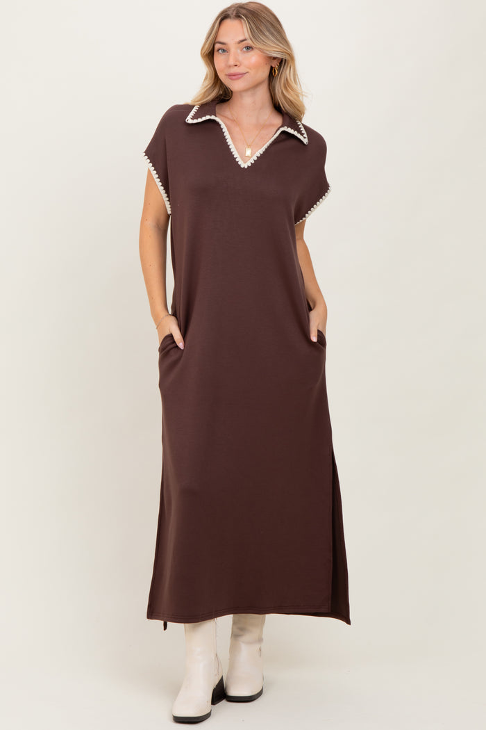 woman wearing a brown maxi dress with a white collar and pockets, standing against a neutral background