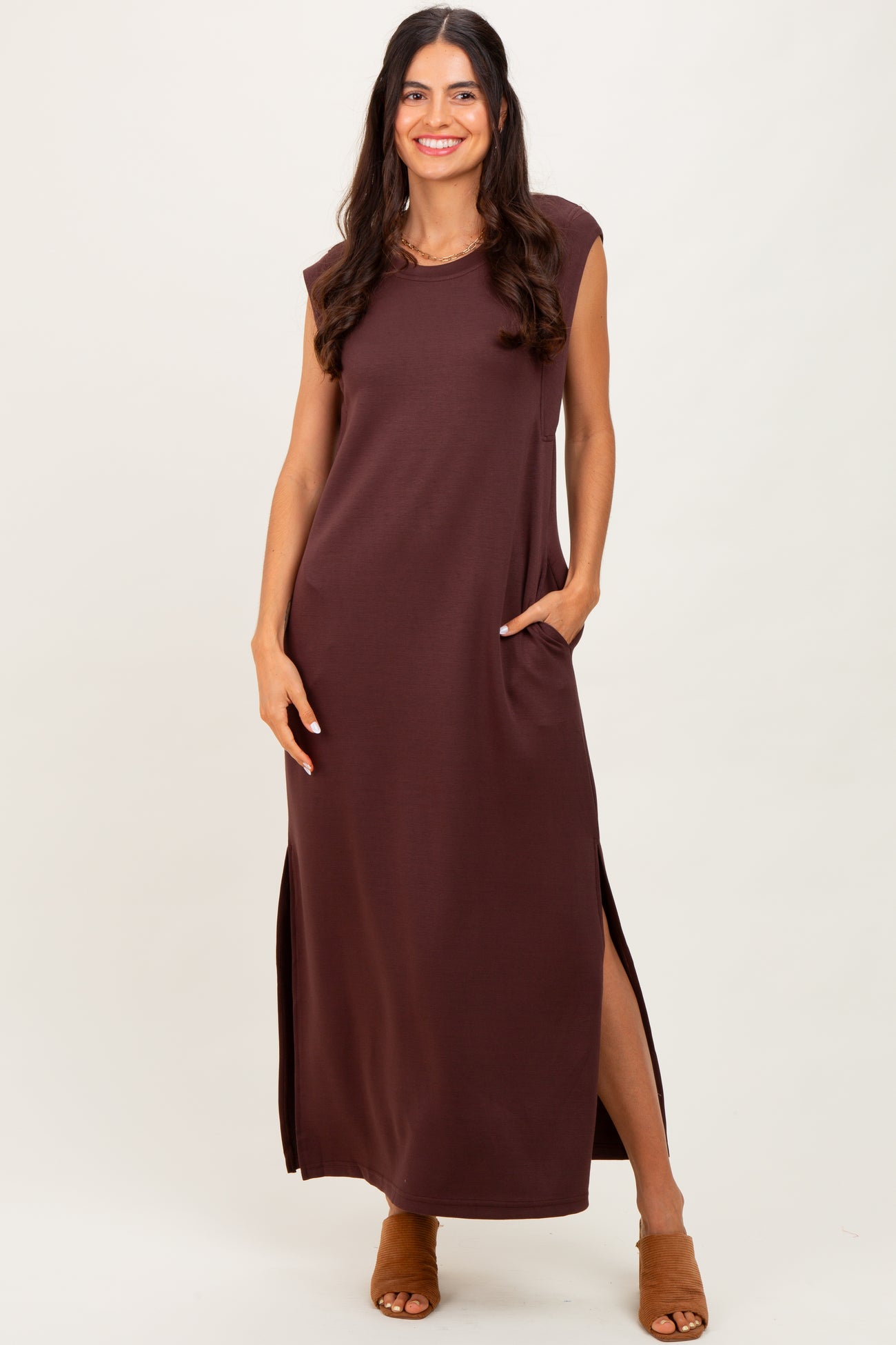 woman wearing a brown sleeveless maxi dress with side pockets and side slits