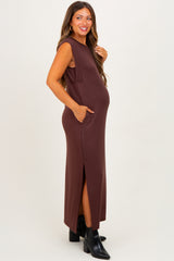 woman wearing a brown sleeveless maternity maxi dress with side slits and pockets, showcasing her baby bump