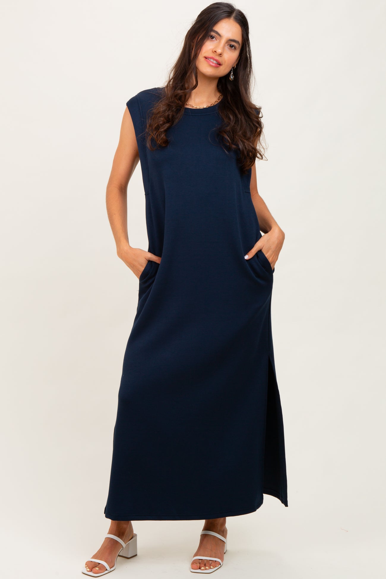 woman wearing a navy blue sleeveless maxi dress with pockets and a side slit