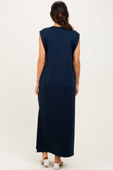woman wearing a navy blue sleeveless maxi dress, view from the back showing a long silhouette and side slits