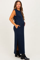 woman wearing a navy blue sleeveless maternity maxi dress with side pockets and a visible baby bump