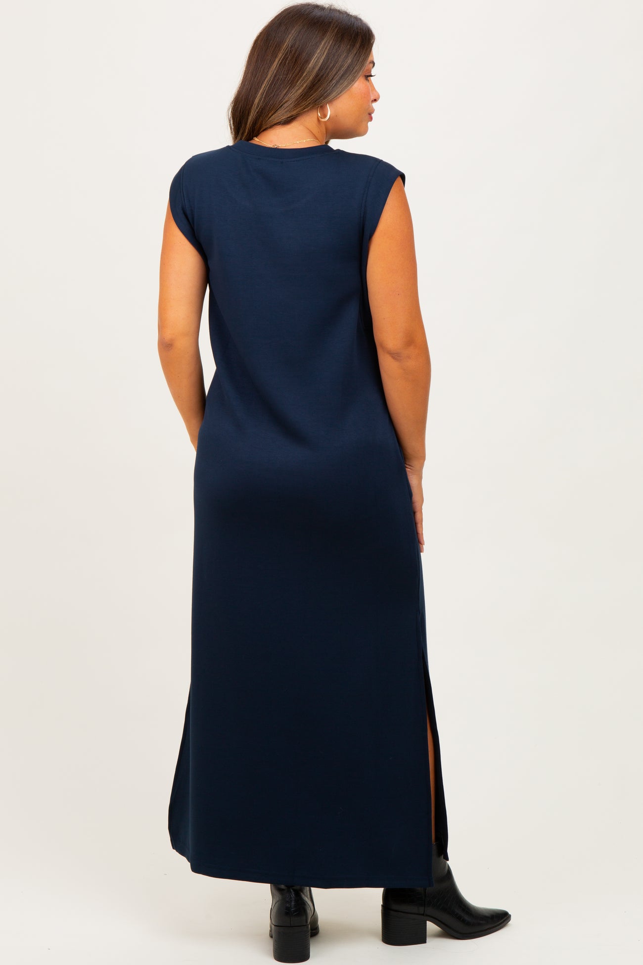 woman wearing a navy blue maternity maxi dress with cap sleeves and side slits, showing no visible baby bump